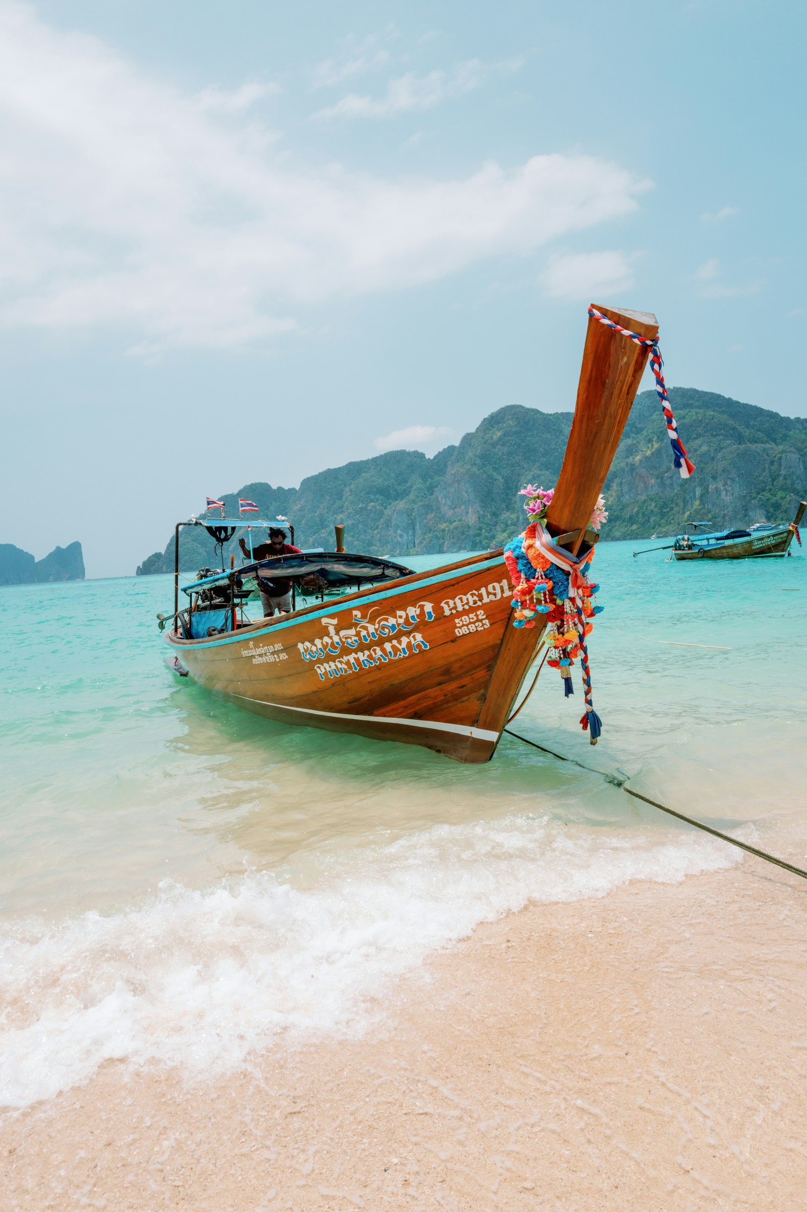 A traditional boat in clear turquoise water beside a tropical beach